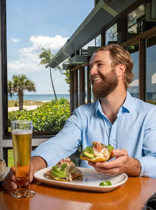 Guest enjoying a meal and drink at Sea Watch on the Ocean with ocean views