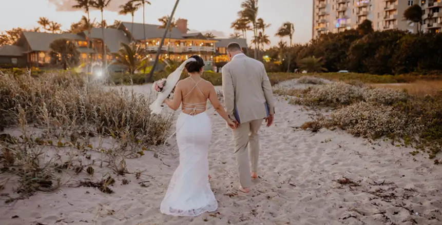 Bride and groom walking hand in hand on the beach at Sea Watch on the Ocean